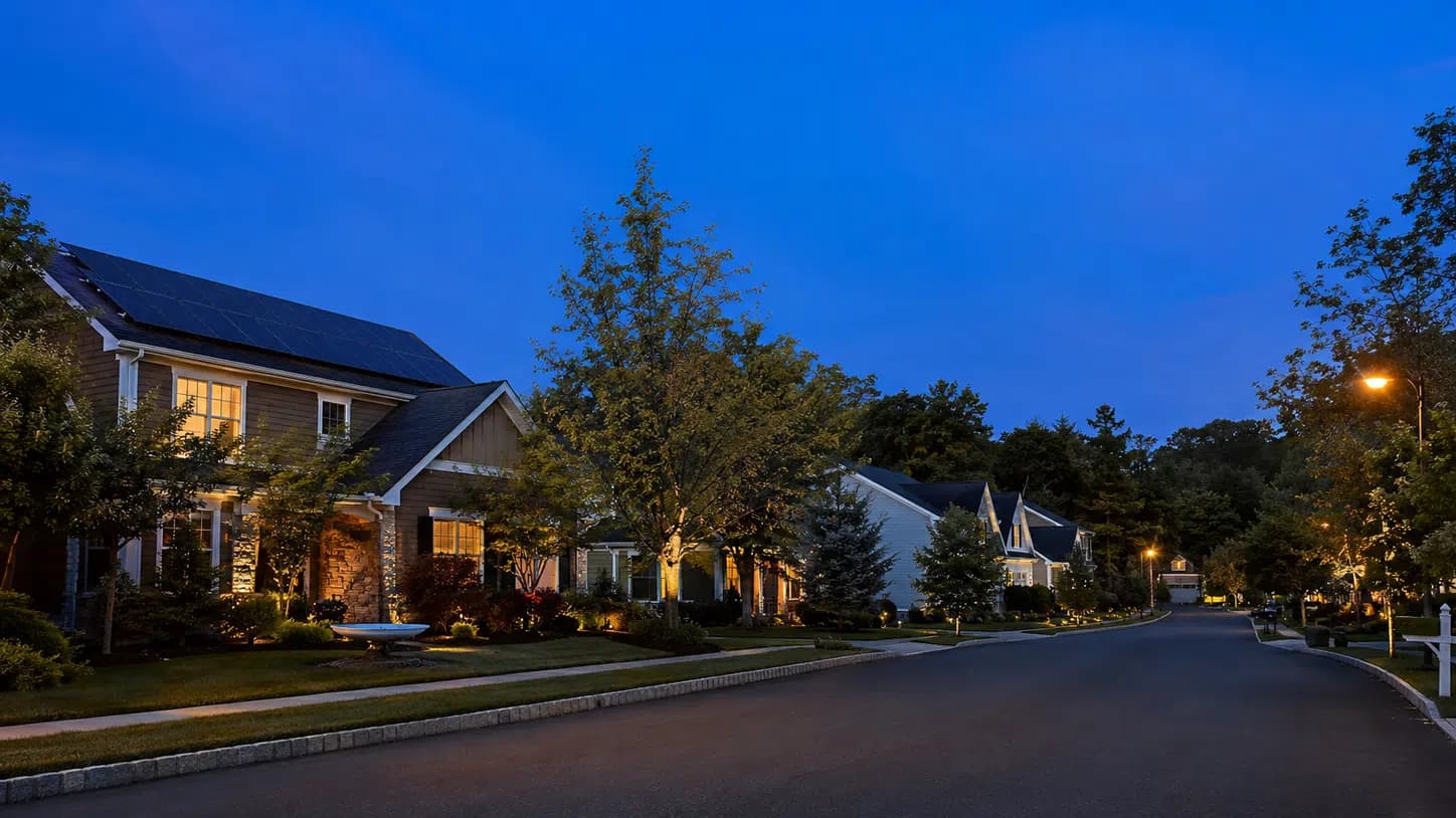 Illustration of a quiet suburban street at twilight with solar-equipped homes, used to contrast the broker and installer paths